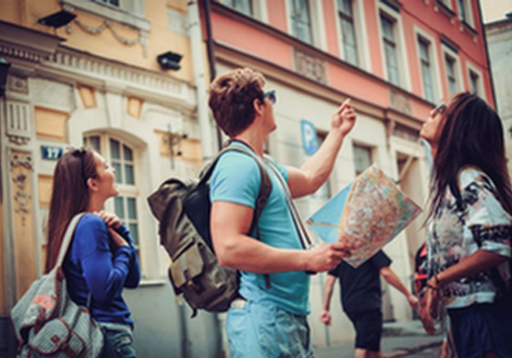 Auf dem Foto sind drei junge Touristen zu sehen, die mit einer Karte eine Stadt entdecken.