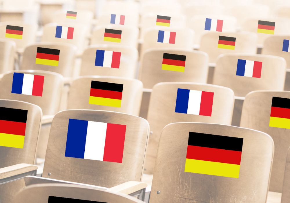 Das Bild zeigt die Stühle eines Hörsaals, auf welchen deutsche und französische Flaggen abgebildet sind.