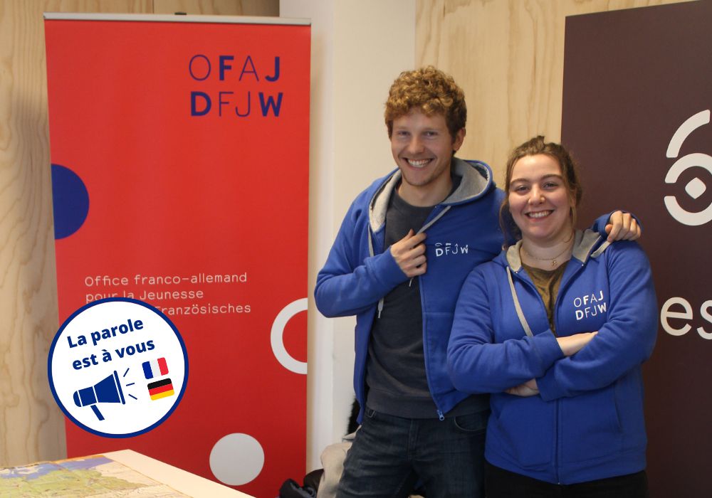 Das Foto zeigt zwei Personen, die an einem Informationstisch stehen und über das DFJW (OFAJ), das deutsch-französische Jugendwerk informieren.