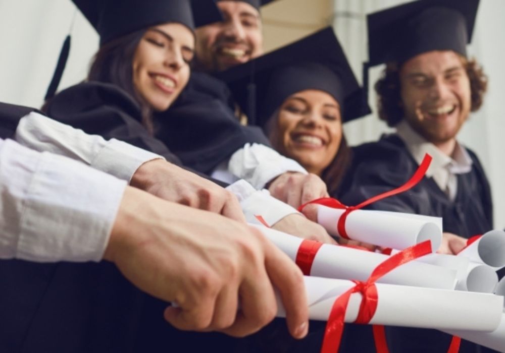 Das Bild zeigt mehrere Studierende, die ihre Diplome in der Hand halten.